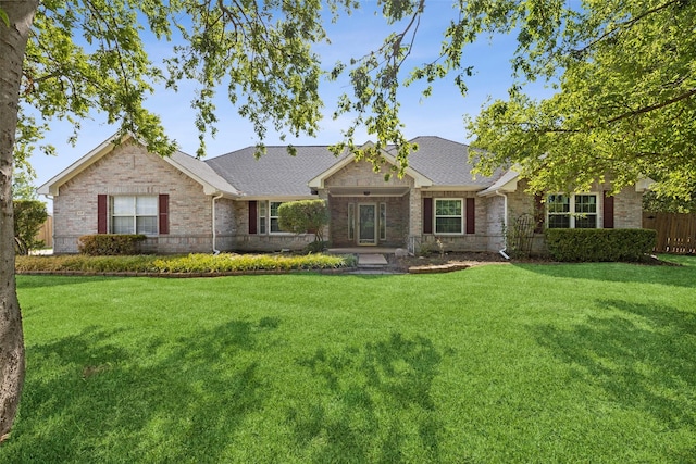 single story home featuring brick siding, a shingled roof, fence, and a front yard