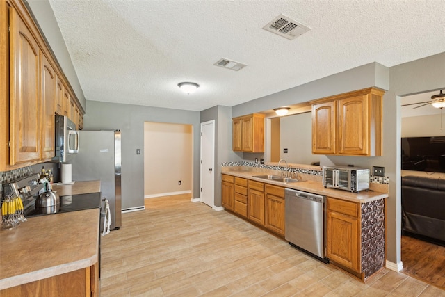 kitchen featuring appliances with stainless steel finishes, visible vents, a sink, and light wood finished floors