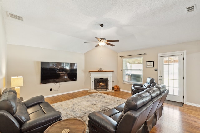 living room featuring ceiling fan, light hardwood / wood-style floors, a textured ceiling, and vaulted ceiling