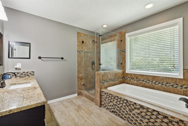 bathroom featuring wood-type flooring, shower with separate bathtub, a textured ceiling, and vanity