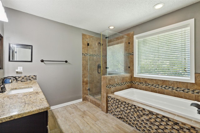 bathroom with wood finished floors, a textured ceiling, vanity, a shower stall, and a bath