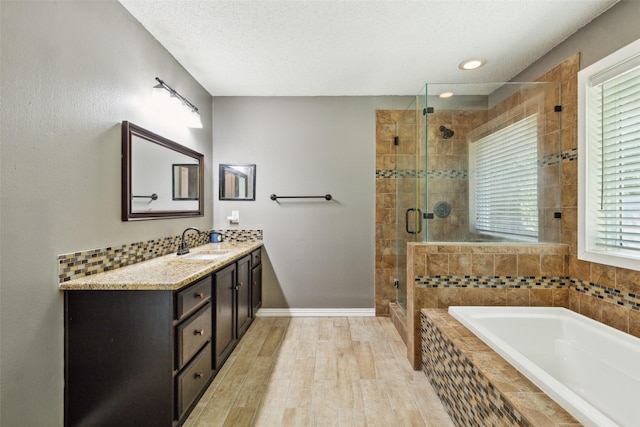 full bathroom with a garden tub, a stall shower, vanity, a textured ceiling, and wood finished floors