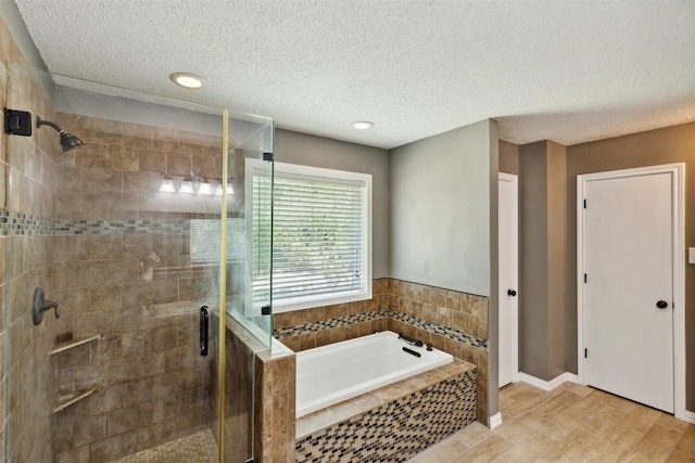 bathroom with separate shower and tub, wood-type flooring, and a textured ceiling