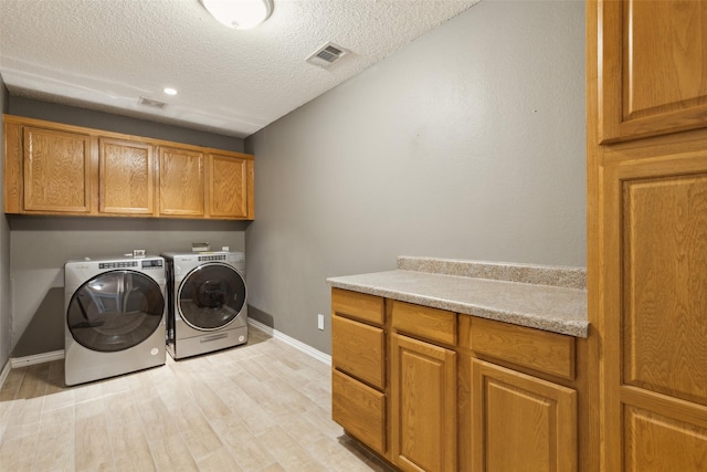 laundry area with a textured ceiling, visible vents, light wood-style floors, independent washer and dryer, and cabinet space