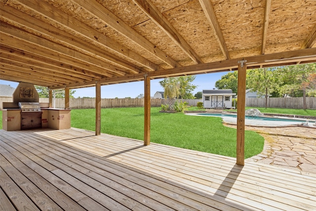 deck with a fenced in pool, a yard, an outdoor kitchen, and a shed