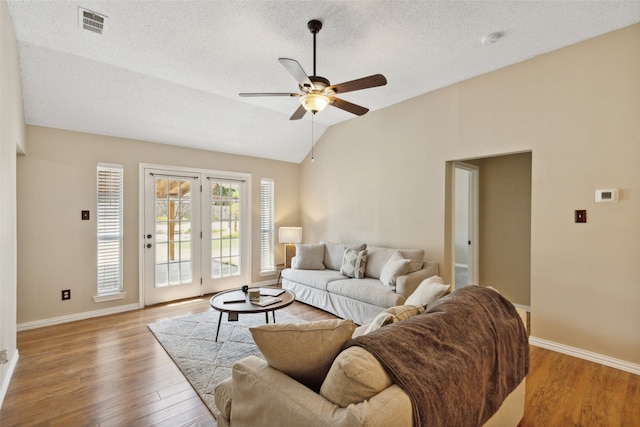 living room with lofted ceiling, ceiling fan, hardwood / wood-style flooring, and a textured ceiling