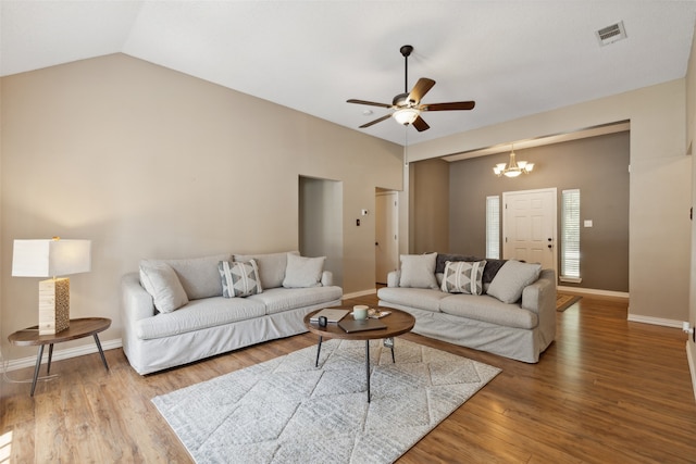 living room featuring ceiling fan with notable chandelier, vaulted ceiling, and wood-type flooring