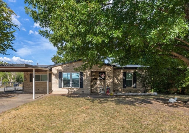 ranch-style home with brick siding, concrete driveway, fence, an attached carport, and a front lawn