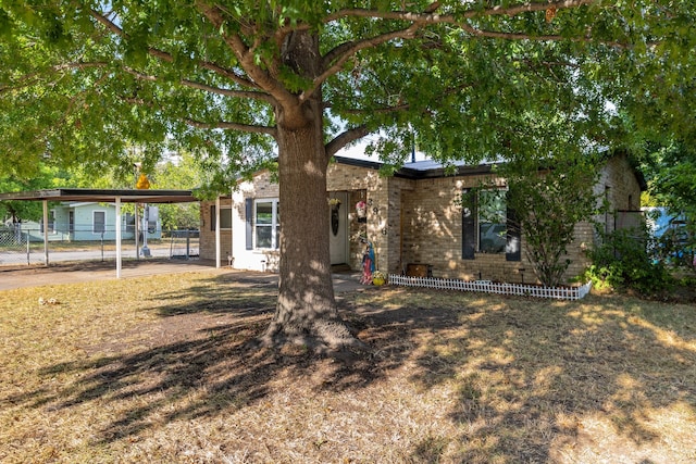 view of front facade featuring a carport, brick siding, and fence