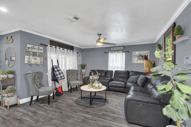 living room with baseboards, visible vents, ceiling fan, wood finished floors, and crown molding