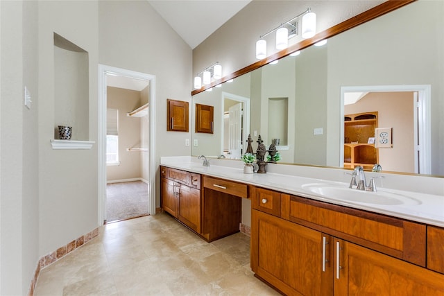 bathroom featuring double vanity, baseboards, vaulted ceiling, and a sink