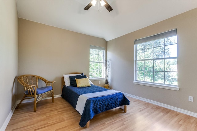 bedroom featuring light wood finished floors, baseboards, vaulted ceiling, and a ceiling fan