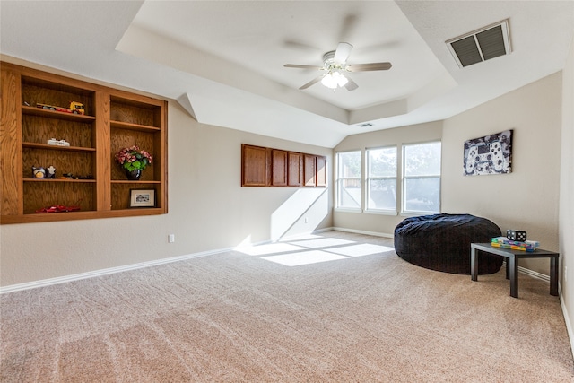 interior space with light colored carpet, ceiling fan, and a raised ceiling