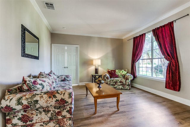 living area with baseboards, a healthy amount of sunlight, wood finished floors, and crown molding