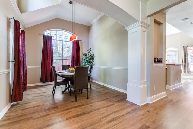 dining space featuring lofted ceiling, ornamental molding, light hardwood / wood-style floors, and ornate columns