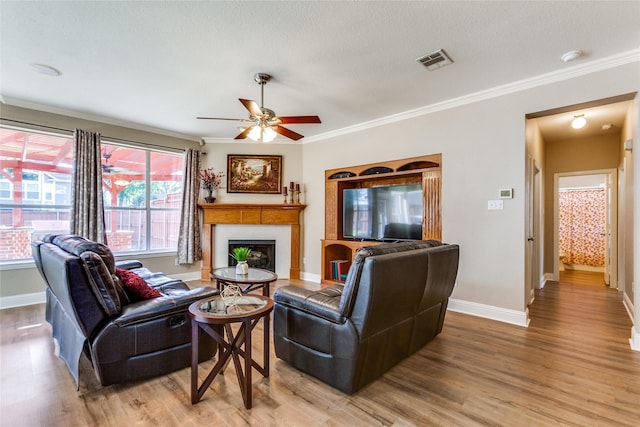 living area with light wood-type flooring, visible vents, a fireplace, and baseboards