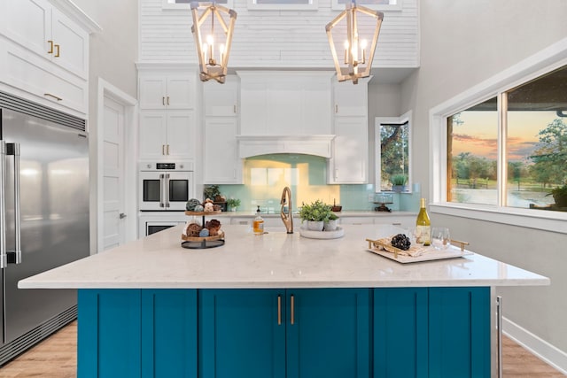 kitchen with pendant lighting, a center island with sink, and built in refrigerator