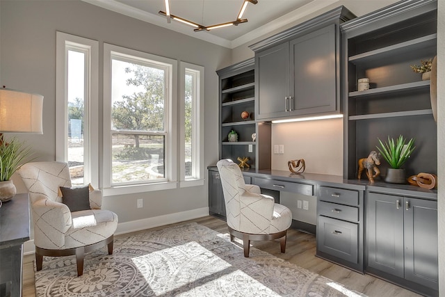 office featuring light wood-type flooring, built in desk, a chandelier, and ornamental molding