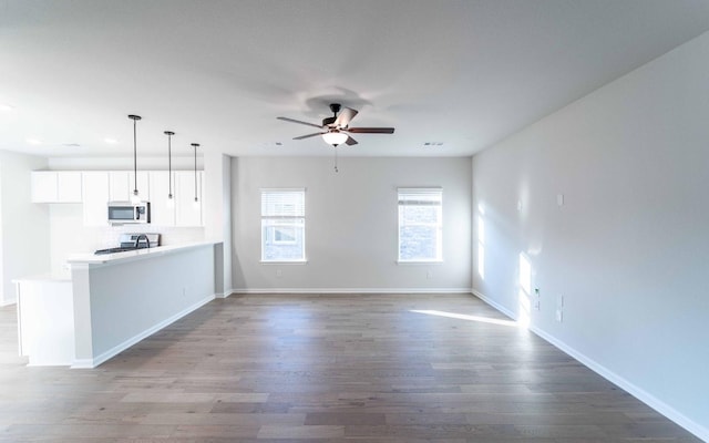 unfurnished living room with wood-type flooring and ceiling fan