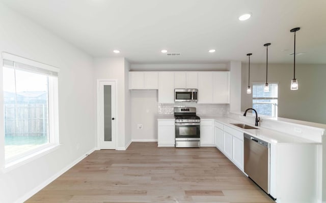 kitchen featuring tasteful backsplash, stainless steel appliances, sink, pendant lighting, and white cabinets