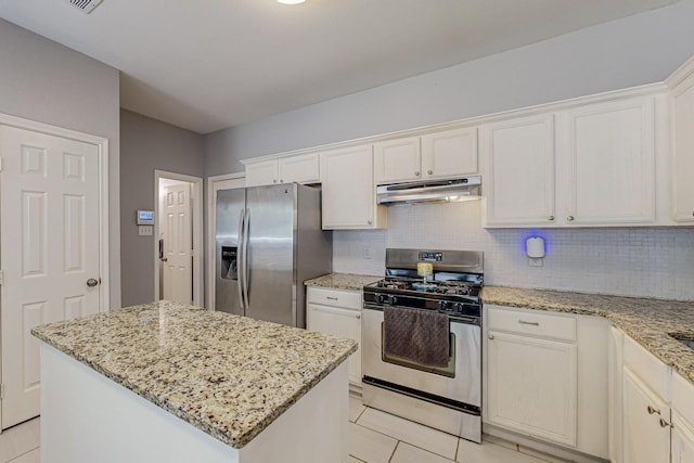 kitchen featuring a center island, light tile patterned floors, appliances with stainless steel finishes, light stone counters, and white cabinetry