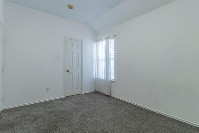 empty room with dark carpet and vaulted ceiling