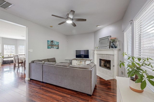 living room featuring a fireplace, dark wood-type flooring, and ceiling fan