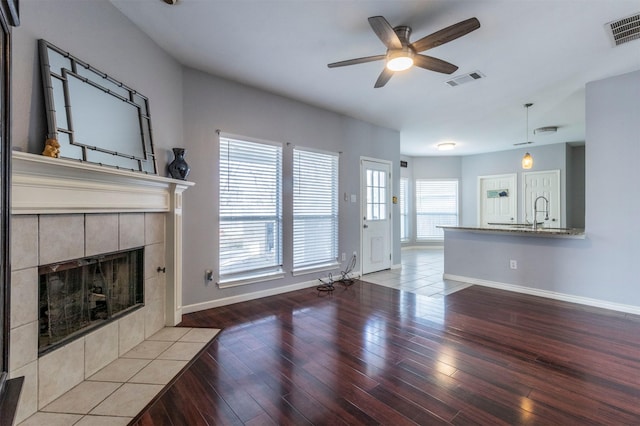 unfurnished living room with a tile fireplace, ceiling fan, and light hardwood / wood-style flooring