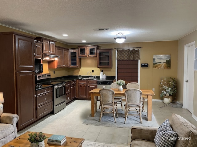 kitchen featuring visible vents, dark countertops, stainless steel appliances, under cabinet range hood, and a sink