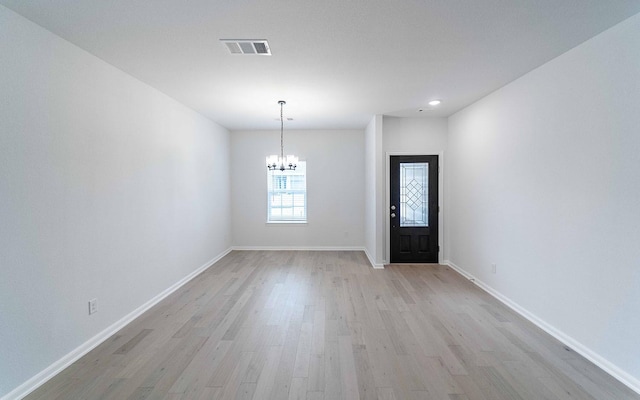 entryway with light wood-style floors, a chandelier, visible vents, and baseboards