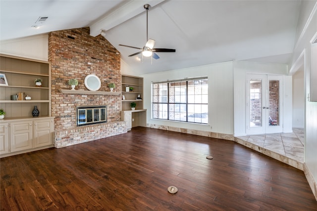 unfurnished living room with built in shelves, ceiling fan, a brick fireplace, lofted ceiling with beams, and dark hardwood / wood-style floors