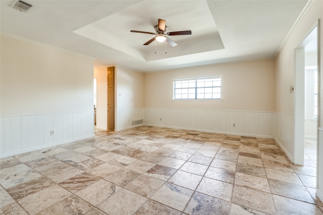 empty room with a tray ceiling, ceiling fan, and crown molding