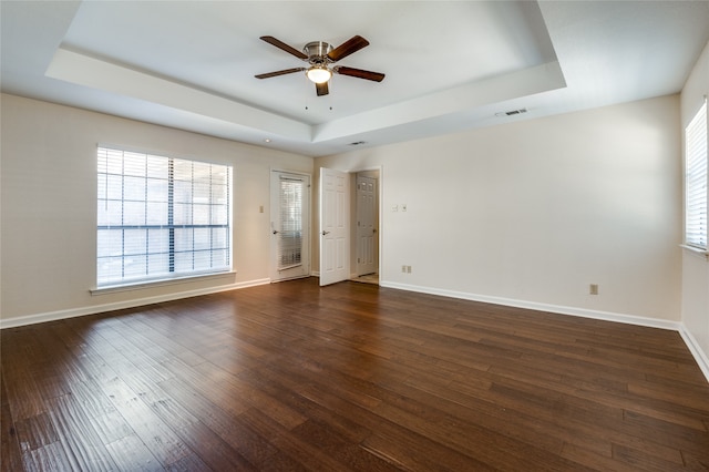 spare room featuring a tray ceiling, ceiling fan, and dark hardwood / wood-style flooring