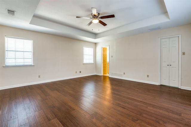 spare room featuring dark hardwood / wood-style flooring, a raised ceiling, and ceiling fan