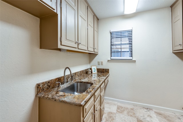 interior space featuring a textured ceiling, light stone countertops, and sink