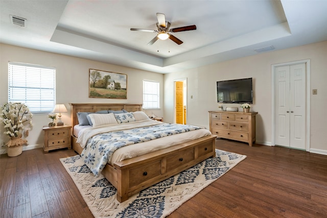 bedroom featuring dark hardwood / wood-style floors, ceiling fan, and a tray ceiling