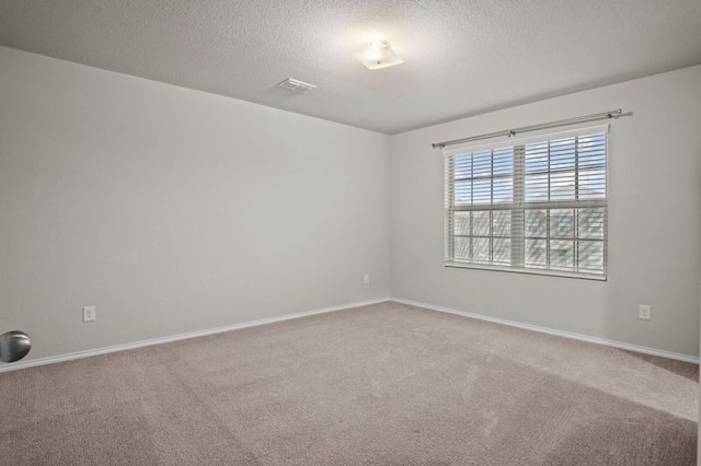 empty room featuring a textured ceiling and light colored carpet