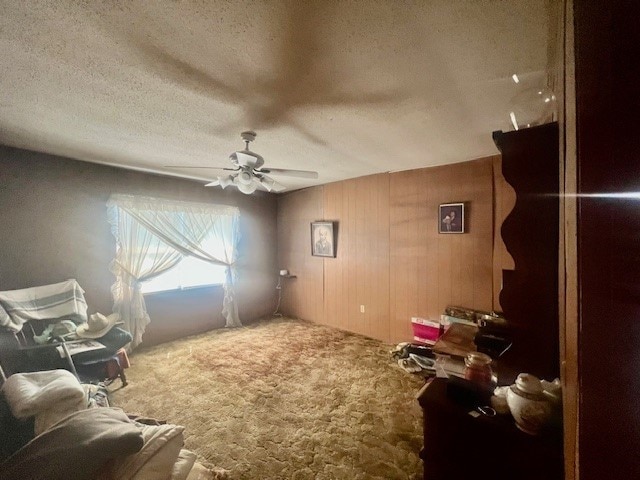 interior space with a textured ceiling, carpet, and ceiling fan