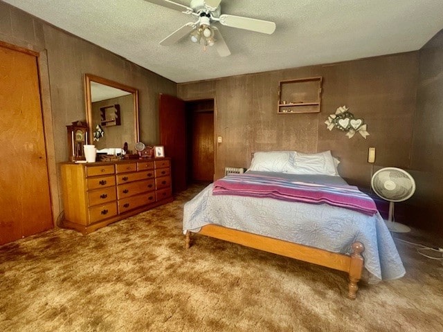 bedroom featuring a textured ceiling, wooden walls, ceiling fan, and carpet