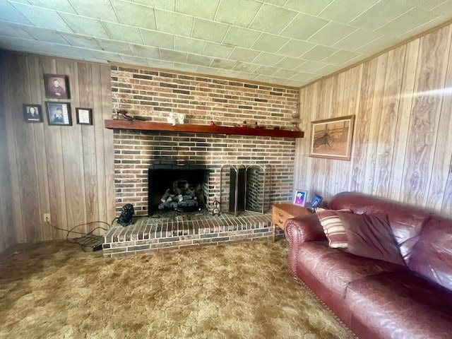 carpeted living room featuring wooden walls and a fireplace