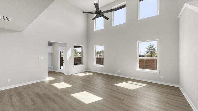 unfurnished living room featuring a wealth of natural light, wood-type flooring, and a high ceiling