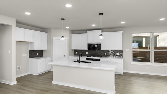 kitchen featuring decorative light fixtures, sink, white cabinetry, a kitchen island with sink, and dark hardwood / wood-style flooring