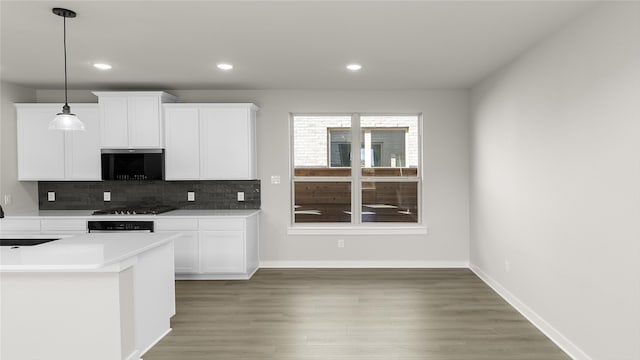 kitchen with hardwood / wood-style floors, decorative backsplash, black gas stovetop, hanging light fixtures, and white cabinets