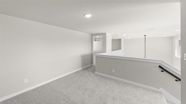 spare room with light carpet and a textured ceiling