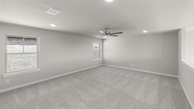 carpeted spare room with ceiling fan and plenty of natural light