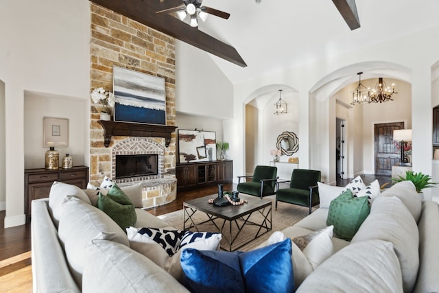 living room featuring arched walkways, beamed ceiling, ceiling fan with notable chandelier, and wood finished floors