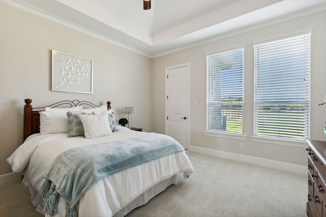 bedroom with a tray ceiling, baseboards, light carpet, and a ceiling fan