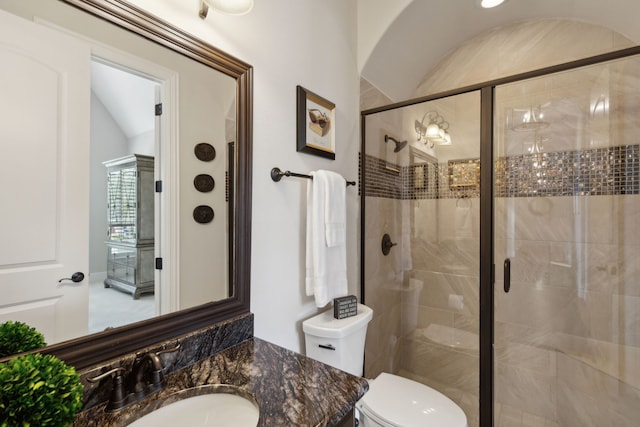 bathroom featuring toilet, a stall shower, and vanity