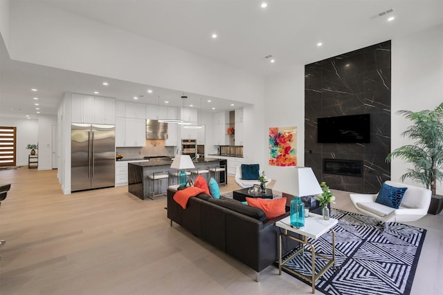 living room featuring a high end fireplace and light hardwood / wood-style floors