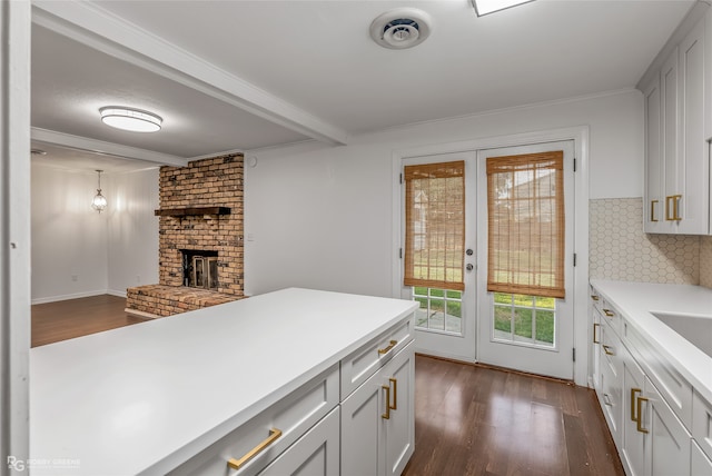 kitchen with backsplash, decorative light fixtures, a brick fireplace, and dark hardwood / wood-style flooring